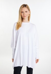 Witte oversized top gemaakt van zachte stof, met lange mouwen, een ronde hals en een ontspannen pasvorm met een iets ongelijke zoom.