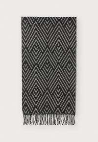 Couverture noire et grise à motifs présentant des lignes géométriques en zigzag avec des bords frangés, fabriquée en tissu doux à texture lisse.