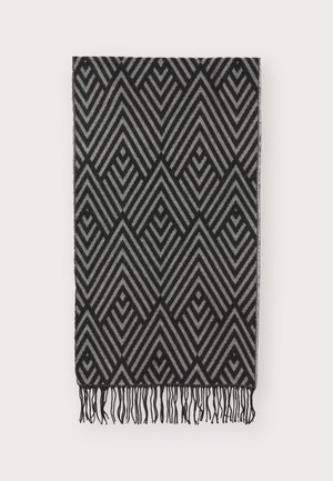 Couverture noire et grise à motifs présentant des lignes géométriques en zigzag avec des bords frangés, fabriquée en tissu doux à texture lisse.