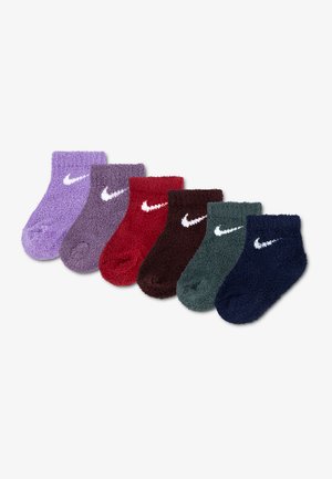 Six paires de chaussettes courtes pelucheuses en violet, lavande, rouge, marron, vert et marine, chacune avec un logo Nike blanc sur le côté.