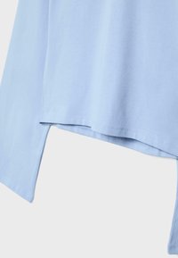 Camicia azzurro chiaro a maniche lunghe con vestibilità rilassata, con orlo curvo e materiale in cotone liscio. Design semplice con accenti minimalisti.