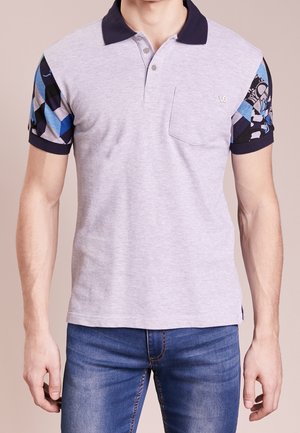 Polo en coton gris avec un col bleu marine et des manches à motifs colorés en bleu, noir et blanc. Doté d'une poche avant et de boutons.