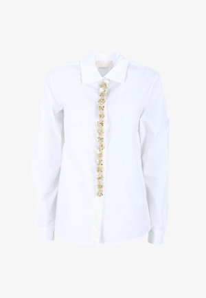 Camicia bianca con bottoni e maniche lunghe, caratterizzata da un'ornamentazione decorativa gialla e trasparente lungo la patta frontale. Tessuto liscio.