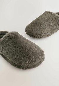 Szare pluszowe kapcie z zaokrąglonym czubkiem i miękką fakturą. Posiadają wyściełany wierzch i zamknięte z tyłu, co zapewnia ciepło i komfort.