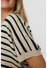 Randig kortärmad topp i beige och svart, tillverkad av mjukt stickat material. Har en avslappnad passform med rullade ärmslut och en subtil textur.