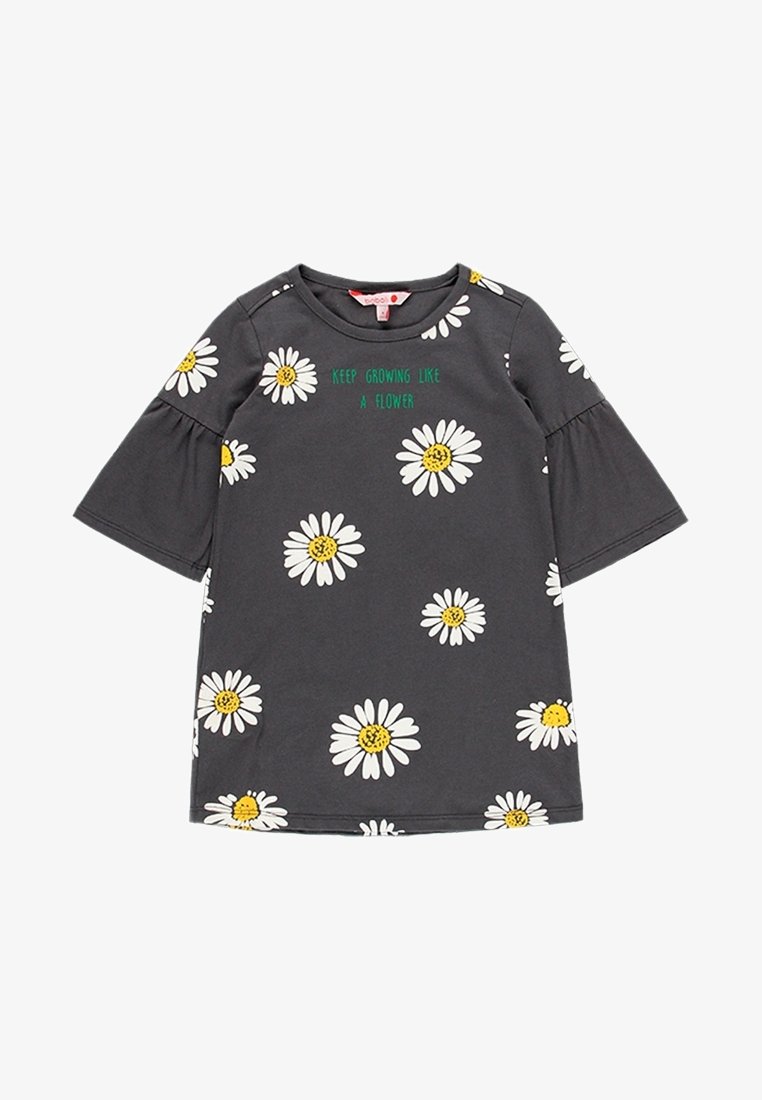 Robe courte à manches courtes gris foncé avec des imprimés de marguerites blanches et jaunes et un texte vert "Continue de grandir comme une fleur" sur la poitrine.