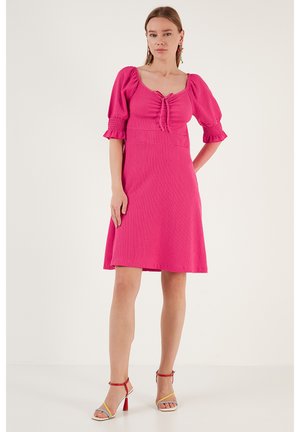 Roze, kort-gek mouwjurk met een aansluitend lijfje en een uitlopende rok. Geverfd stof en strikdetail bij de halslijn.