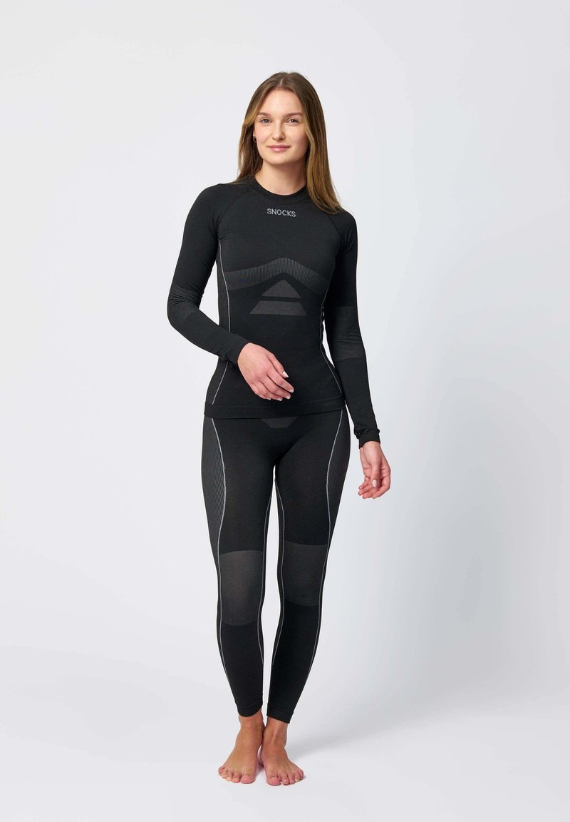 Svart atletisk tvådelad set, med långa ärmar och leggings med texturerade paneler, kontrasterande grå sömmar och en figurnära design.