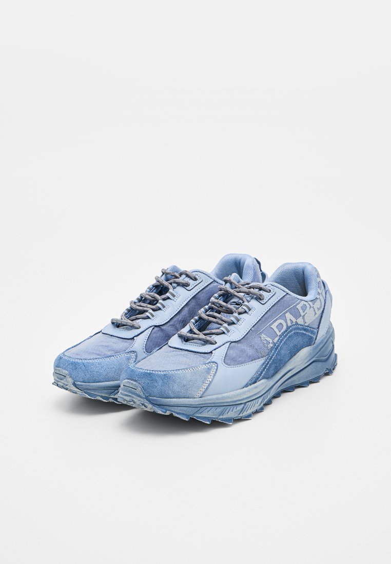 Par de zapatillas deportivas azules con suelas texturizadas, diseño con cordones y paneles de tela superpuestos sobre un fondo blanco.