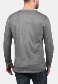 Langärmliges Shirt aus verblasstem grauem Stoff mit rundem Halsausschnitt. Ausgestattet mit einem Lederlogo-Patch am Saum und strukturierter Oberfläche. Eignet sich hervorragend zum Schichten.
