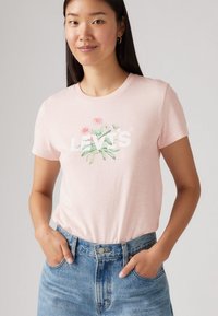 Helles rosa Baumwoll-T-Shirt mit einem Grafikdesign von Blumen und dem „LEVI'S“-Logo in Weiß. Kurze Ärmel und runder Halsausschnitt.