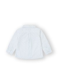 Camisa blanca de manga larga para niño pequeño con pequeños lunares azules, puños abotonados y un pliegue tipo caja en la parte de atrás, dispuesta plana boca abajo.