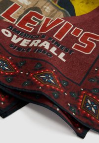 Panno bordeaux con marchio Levi's, recante il testo "America's Finest Overall Since 1850" e decorato con motivi geometrici multicolori sui bordi.