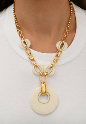 Collier doré avec des maillons en résine crème de forme circulaire et un grand pendentif crème avec un anneau intérieur concentrique.