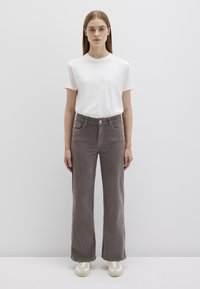 White short-sleeve t-shirt paired with high-waisted, wide-leg gray corduroy pants. Pants feature front pockets and a button closure.