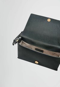 Borsa a tracolla in pelle nera con texture, chiusura magnetica, che mostra un interno di colore chiaro con un motivo sottile e un'etichetta del marchio all'interno.