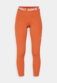 Legginsy Nike Pro w żywym pomarańczowym kolorze, wykonane z elastycznego materiału. Posiadają wysoką talię z napisem "PRO NIKE" na białym tle, gładki i dopasowany krój.