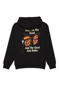 Zwarte hoodie met een grote vlinderafbeelding in oranje en zwart, met een loep-effect. De tekst luidt: "Focus op het Goede."