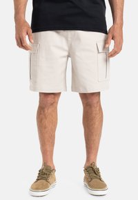 Bermudas cargo beige hasta la rodilla con dos bolsillos laterales, hechas de tejido de algodón, con costuras resistentes y un corte relajado.