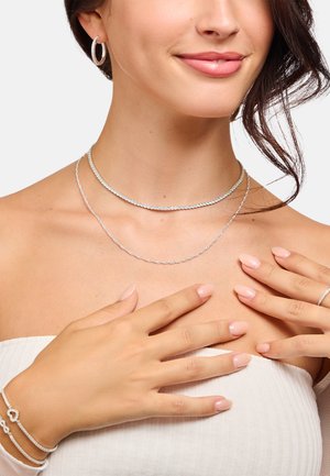 Silberschmuckset mit zwei geschichteten Halsketten mit filigranen Designs, Creolen und einem Armband. Glatte, polierte Oberflächen und edle Texturen.