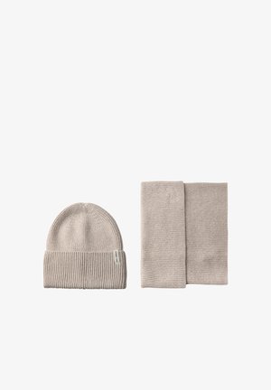 Lys beige strikket hue med ribbet tekstur og matchende ribbet tørklæde, begge med et enkelt design uden yderligere detaljer.