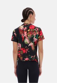 Koszulka z krótkim rękawem w czarny kwiatowy wzór, z wyrazistymi różami i zielenią, wykonana z lekkiego materiału o gładkiej teksturze.