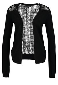 Svart kashmirtröja med långa ärmar och öppen framsida. Har ett vitt mönstrat panel som löper ner i mitten, med texturerade spetsdetaljer på axlarna.