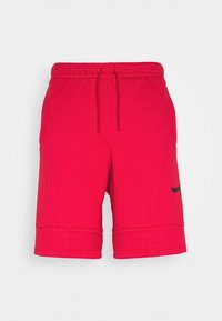 Rote Baumwollshorts mit elastischem Bund und Kordelzug, ausgestattet mit seitlichen Taschen und einem schwarzen Logo-Akzent am linken Bein.