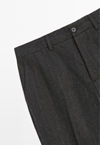 Pantaloni grigio scuro realizzati in un tessuto texturizzato con un sottile motivo a righe. Presentano una chiusura con bottone e un design a gamba dritta.