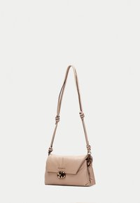 Bolso de hombro de cuero beige con una correa anudada y un cierre circular metálico, que cuenta con un cierre de solapa y una textura suave.