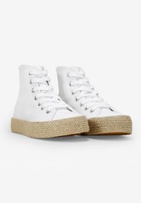 Zapatillas altas de lona en blanco con suela de yute estilo espadrille texturizada, que presentan ojales de metal y diseño de cordones.