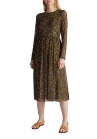 Brun blommönstrad klänning med långa ärmar, rund halsringning och smockad midja, tillverkad av lättviktig tyg. Buren med platta sandaler.