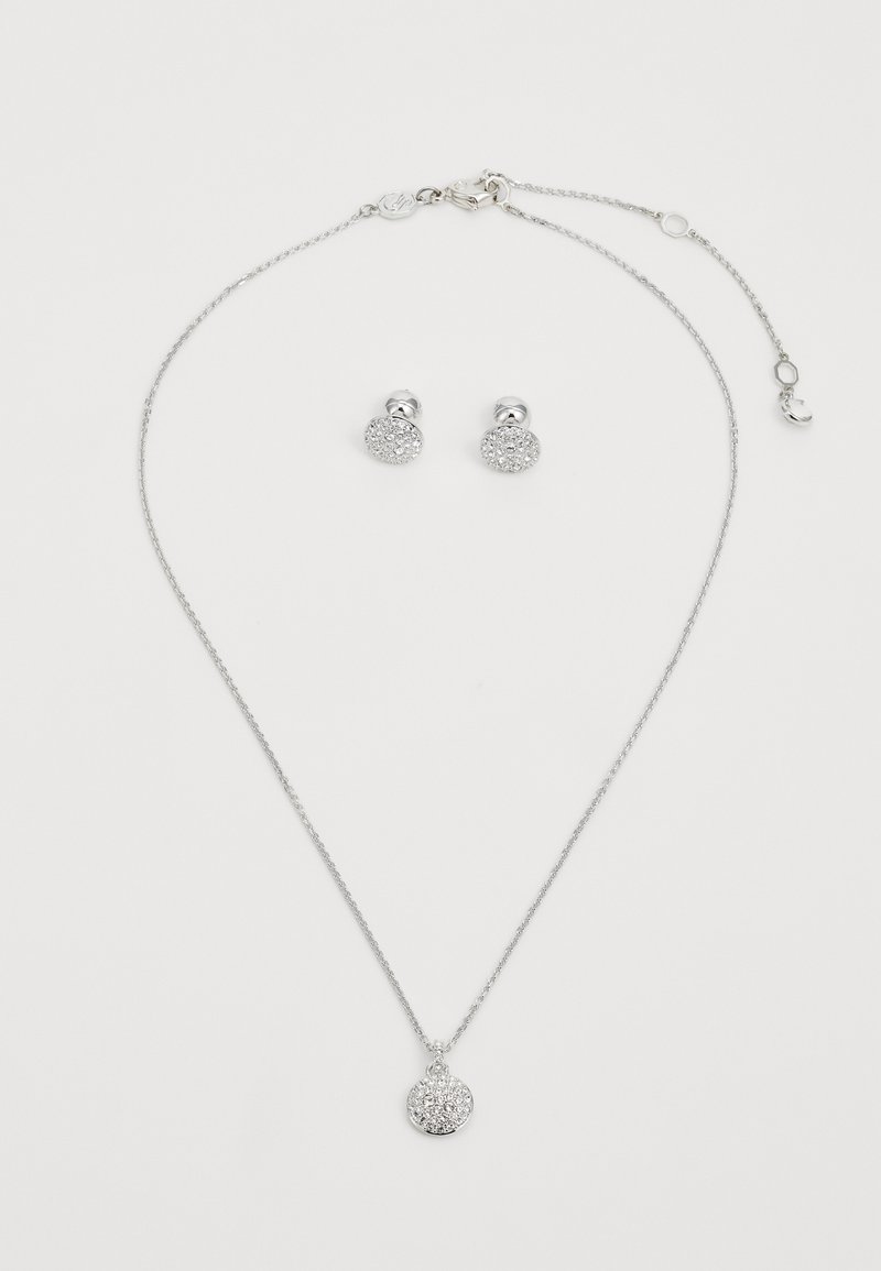Conjunto de joias em tom prateado, apresentando um colar delicado com uma corrente e um pendente redondo e brilhante, além de brincos de botão combinando.