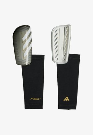 Para czarnych i złotych ochraniaczy na goleń Adidas F50 do piłki nożnej z twardymi osłonami ochronnymi i dopasowanymi rękawami kompresyjnymi.
