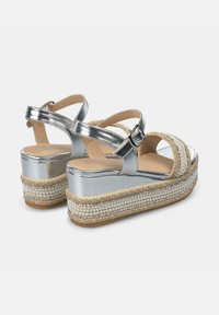 Sandali platform in metallo argentato con un accento in corda intrecciata e perline sulla base, con cinturini alla caviglia regolabili e design con punta aperta.