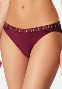 Burgunderfarbene Damenunterhosen mit Spitzenseiten und elastischem Bund, der das wiederholte "ELLE"-Logo zeigt, getragen an einem straffen Oberbauch und den Oberschenkeln.