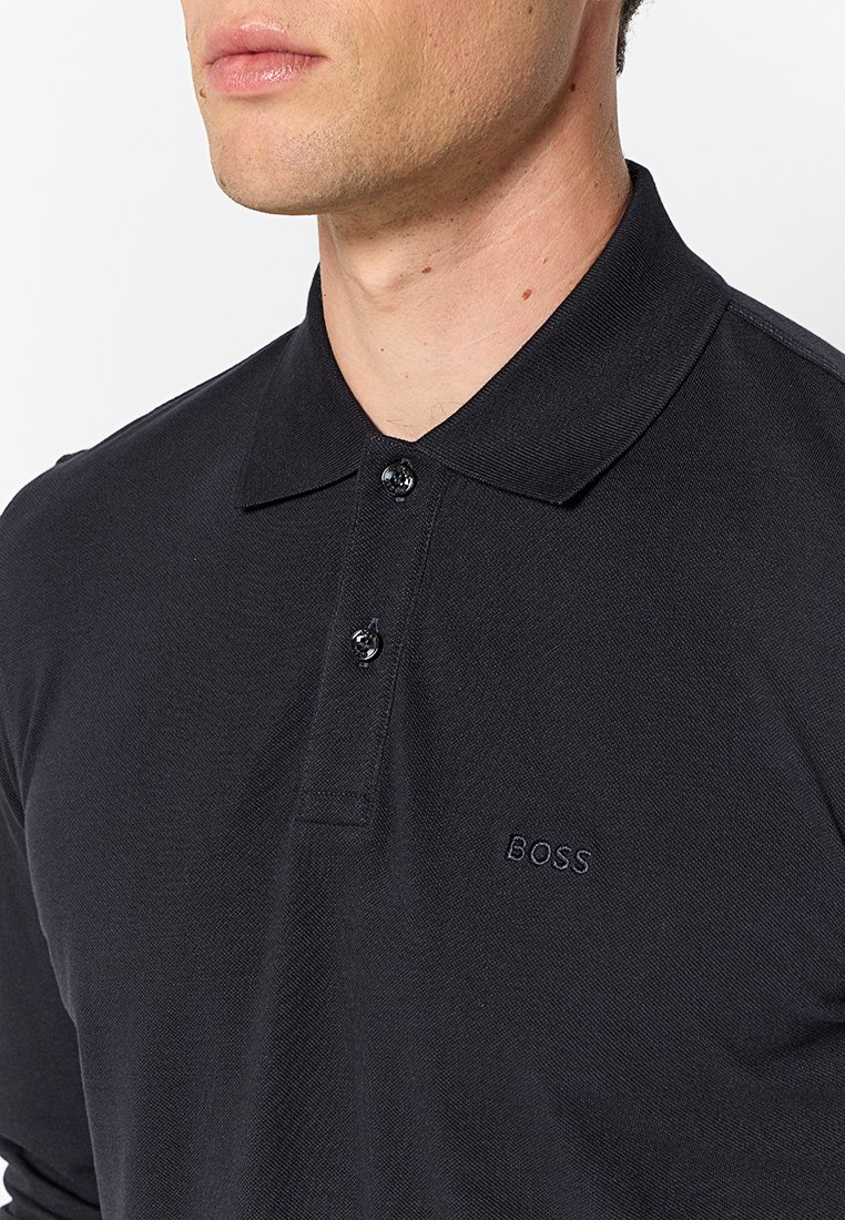 Zwart polo shirt met een kraagontwerp, drie-knoopsluiting en geborduurd "BOSS" logo in bijpassende kleur op de borst.