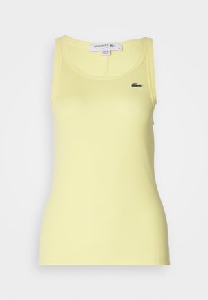 Camiseta de tirantes amarilla con cuello redondo y corte ajustado. Presenta un pequeño logo bordado de Lacoste en el lado izquierdo.