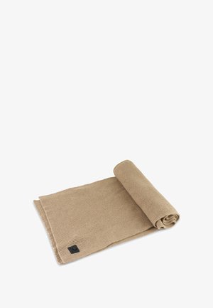 Beige woven textile rolled up, with a textured finish. Features a black tag with logo at one corner. Soft and pliable material.