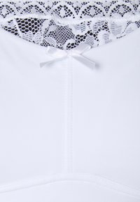 Vestido branco com um acabamento rendado na gola, adornado com um pequeno laço de cetim branco no centro e uma textura de tecido suave.