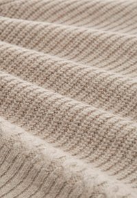 Dzianina w jasnym beżu z teksturowanym wzorem drobnych i grubych pasków. Miły w dotyku, ciepły wygląd z delikatnym połyskiem.