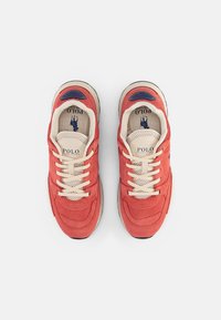 Pair of red and beige Polo Ralph Lauren sneakers with laces, mesh detailing, and logo visible on insoles and tongue, top view.