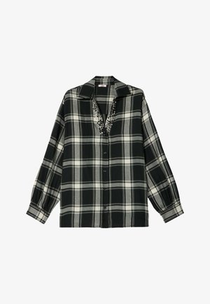 Camicia a quadri bianca e nera con colletto, chiusura frontale a bottoni e scollatura decorata. Maniche lunghe con polsini elasticizzati e una vestibilità comoda.