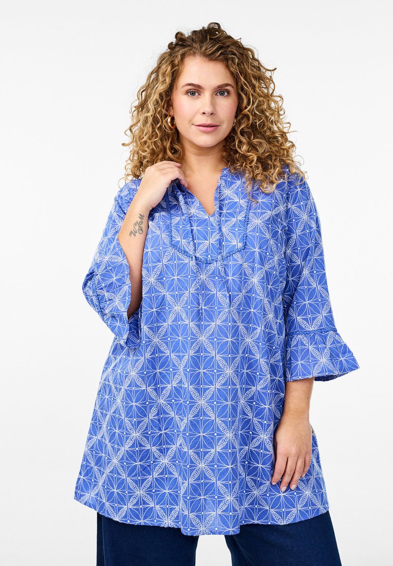 Blauwe tuniek shirt met een geometrisch wit patroon, V-hals en driekwart uitlopende mouwen van lichtgewicht stof.