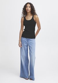 Zwarte ribbed tanktop met brede bandjes, gecombineerd met lichtblauwe high-waisted wijde jeans. Glad textuur, casual pasvorm, minimalistische details.