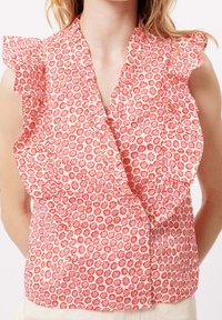 Blumige Bluse mit Rüschensäumen, die einen rosa Hintergrund und rot, orange und weiße Muster aufweist. Leichter Stoff mit Wickeldesign.