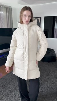 Geacă matlasată bej deschis, cu guler înalt, închidere cu fermoar și buzunare laterale. Materialul pare neted, cu un finisaj ușor lucios.