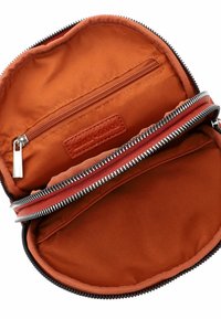 Bolso redondo de textil rojo con un acabado liso. Cuenta con un cierre con cremallera y un bolsillo interior. Forrado con tela a juego de textura suave.