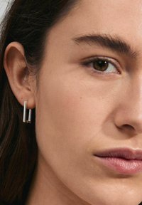 Silver rectangular earrings with a minimalist design, featuring a thin texture and a subtle open space in the center.
