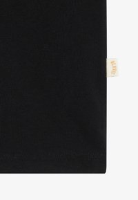 Black cotton t-shirt featuring a soft texture, a straight cut, and a small cream-colored label with "B.L.K.W.S" sewn on the side.